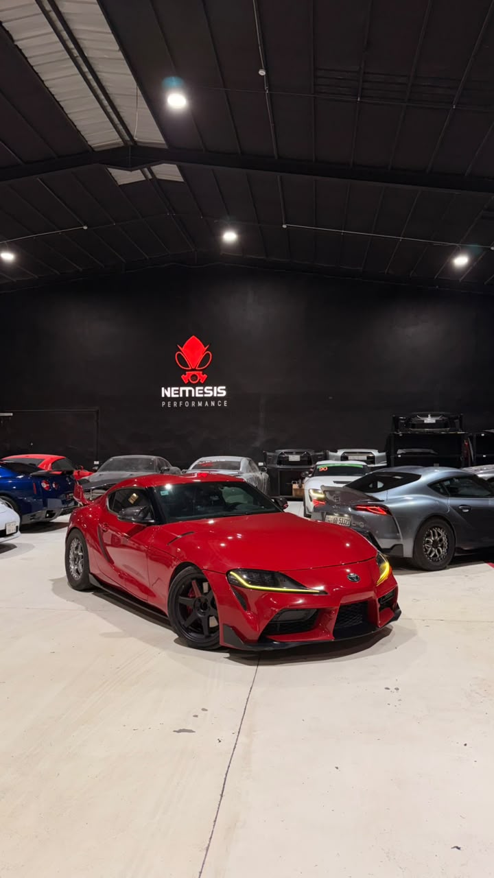 Red Supra with forged wheels in front of the Nemesis Performance sign